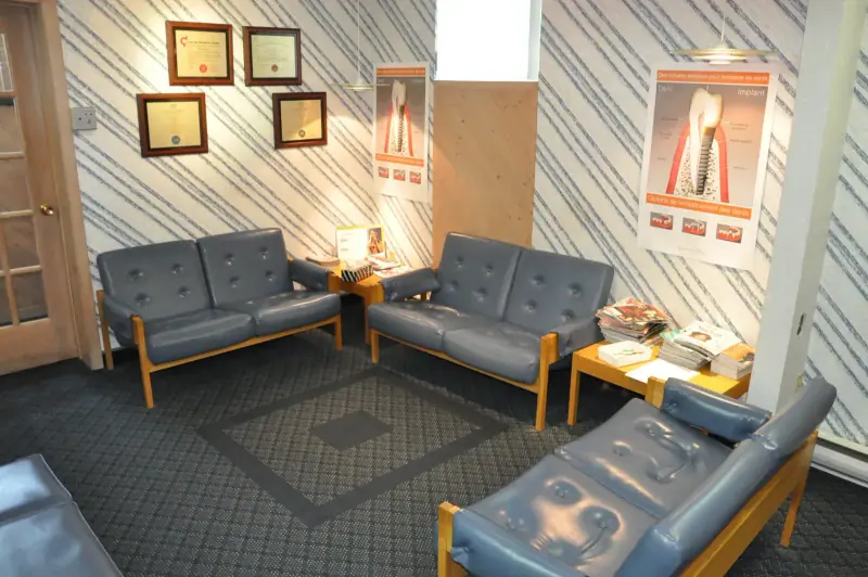 Salle d’attente avec banquettes bleues, diplômes encadrés et affiches éducatives